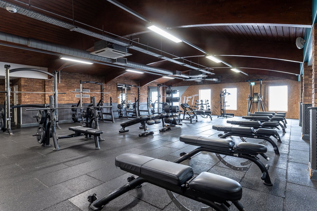 PureGym Northolt: Weight benches, resistance machines, free weights, and exposed brick walls in a gym setting.