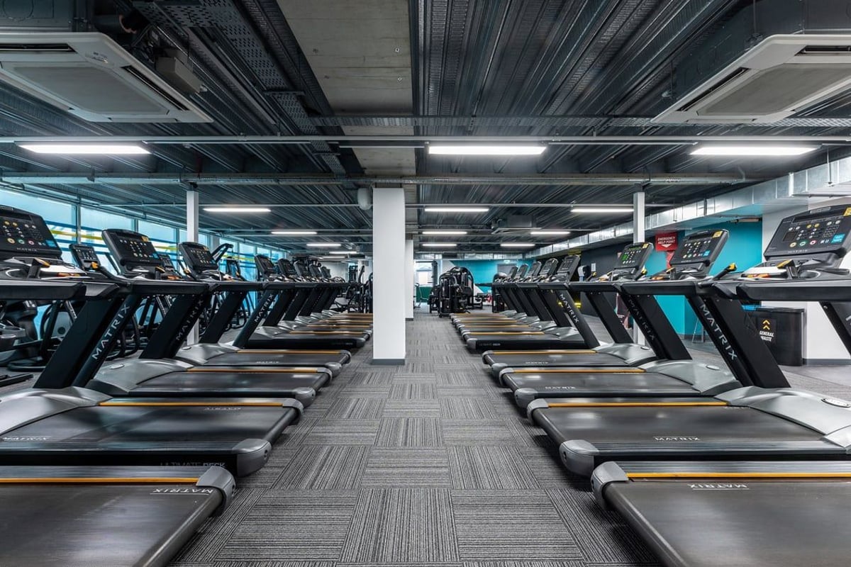 PureGym Newcastle Eldon Garden: Rows of treadmills with digital displays in a sleek, modern gym setting.