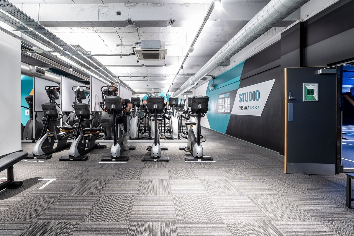 PureGym London Sydenham: Rows of futuristic-looking exercise machines in a studio setting with teal accents.