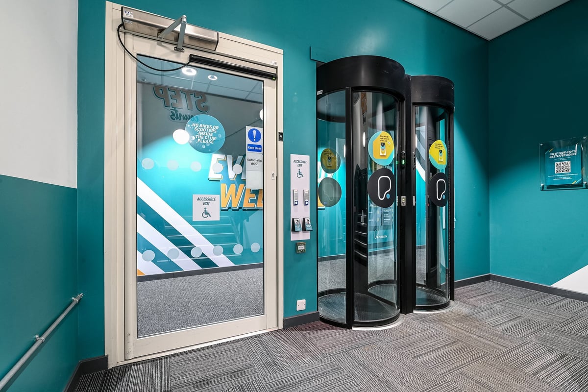 PureGym Canterbury Sturry Road: Swipe entry door, teal walls, and glass entry pods.