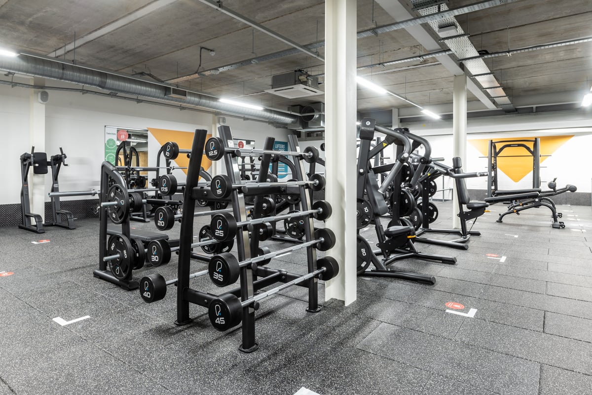 PureGym Plymouth Marsh Mills: Weight racks, benches, dumbbells, and weightlifting platforms in a dimly lit gym space.