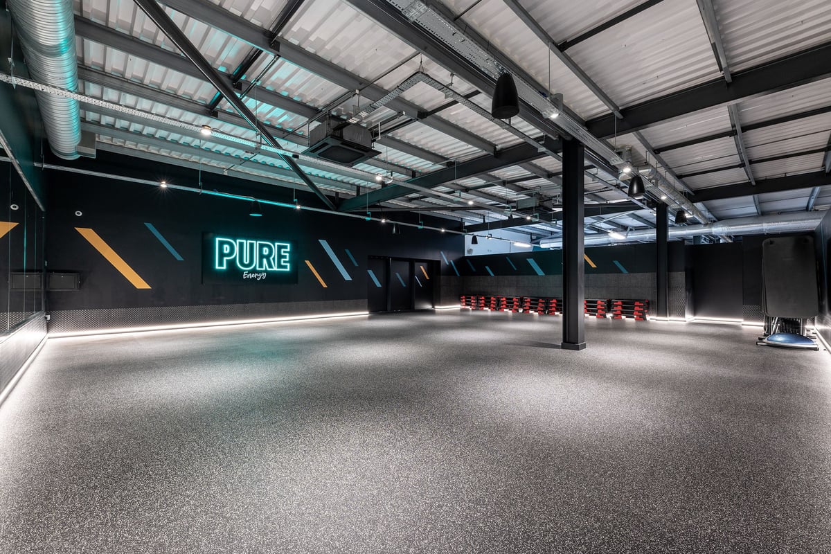 PureGym Reading Basingstoke Road: Rows of treadmills, rubberized flooring, and neon 'PURE' signage in a modern gym studio.