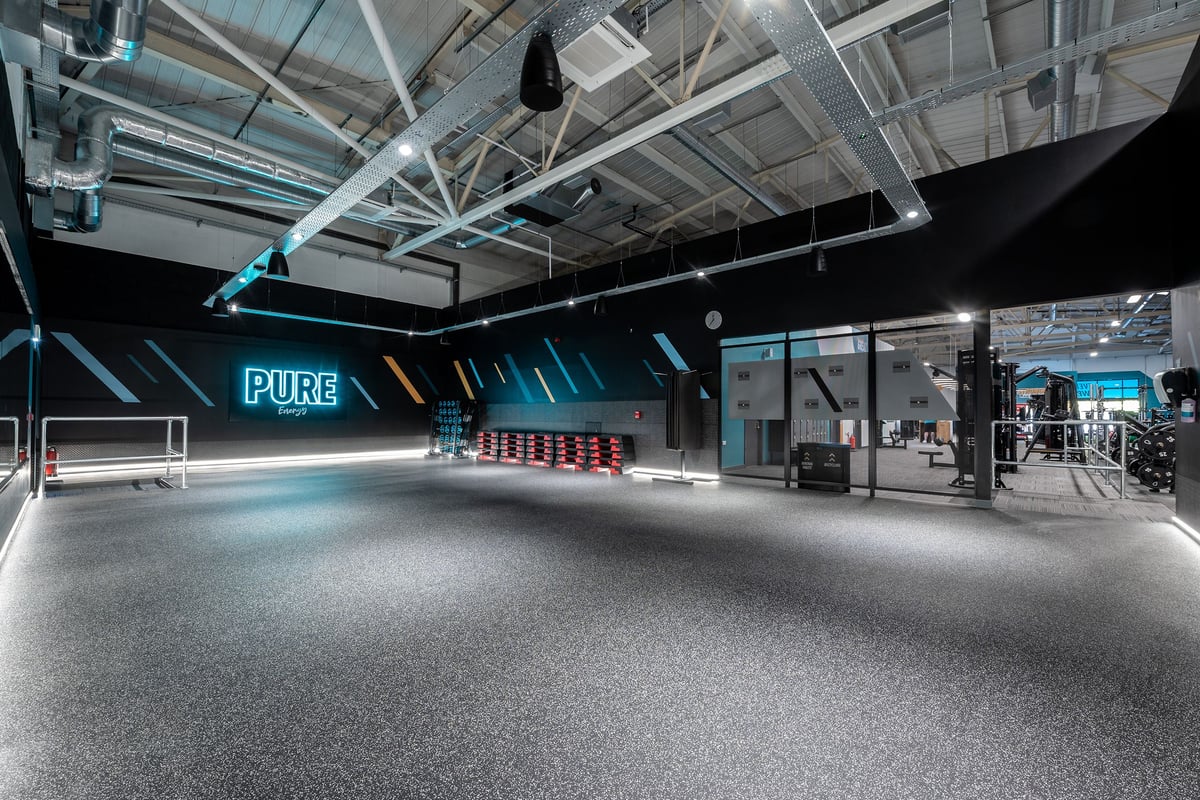 PureGym Taunton: Workout studio with neon signage, rubberized flooring, weight plates, and open space.