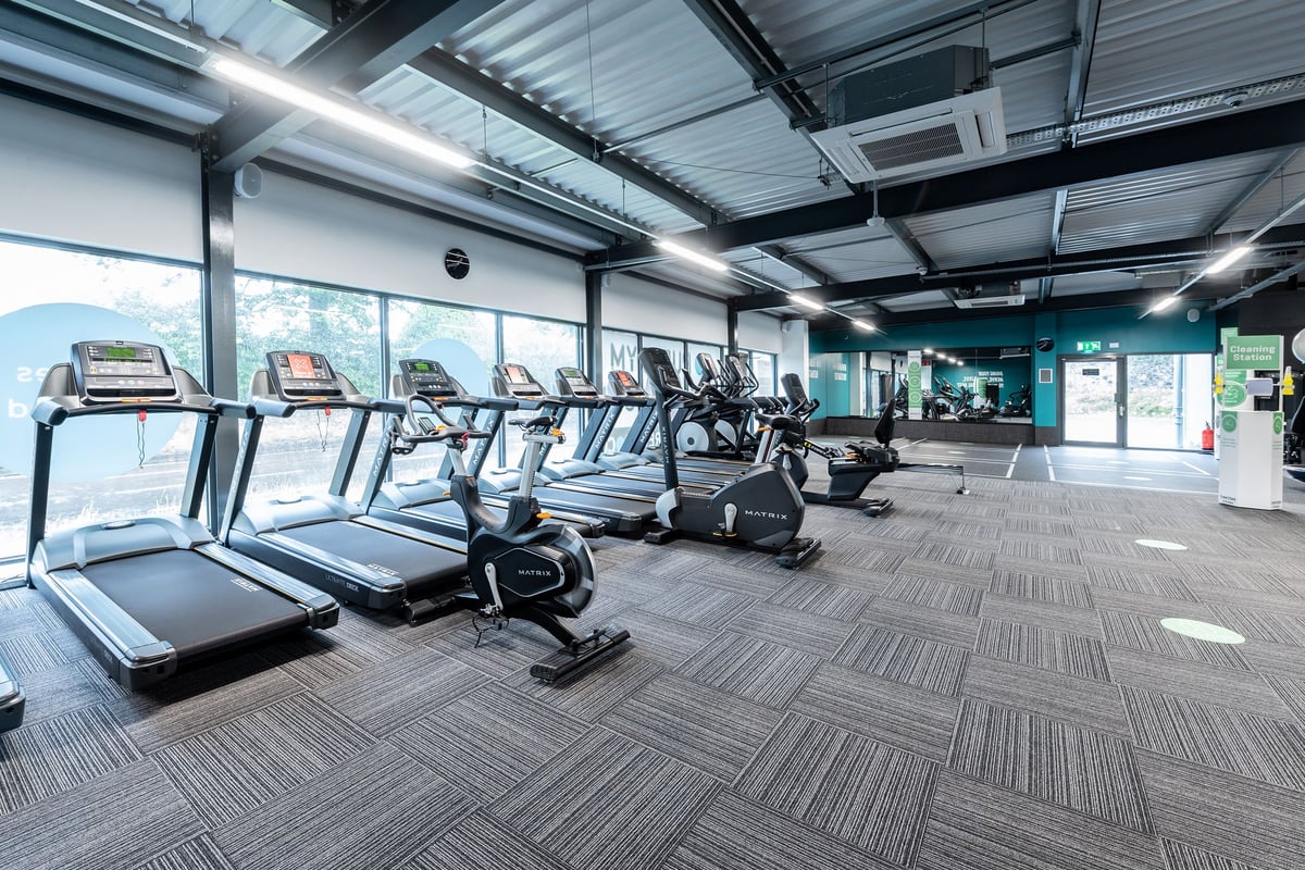 PureGym Kirkcaldy: Rows of treadmills, ellipticals, stationary bikes in a gym with large windows.
