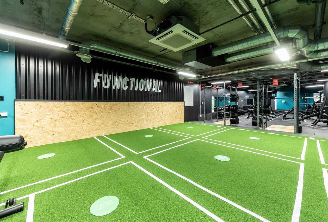 PureGym London Camberwell New Road: Green turf area with markings, weights, and equipment for functional training.