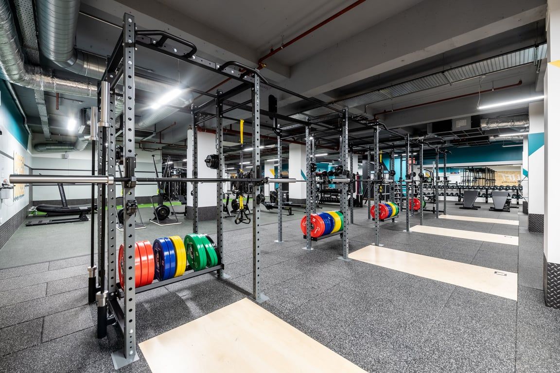 PureGym London Kingston: Weight racks, colourful plates, benches, and rubberised flooring in a well-equipped gym.