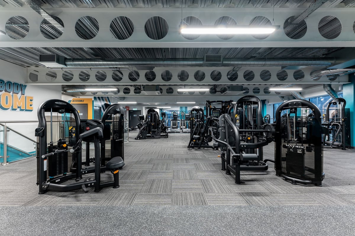 PureGym Manchester First Street: Gym studio with resistance machines, free weights, rubberized flooring, and ceiling vents.