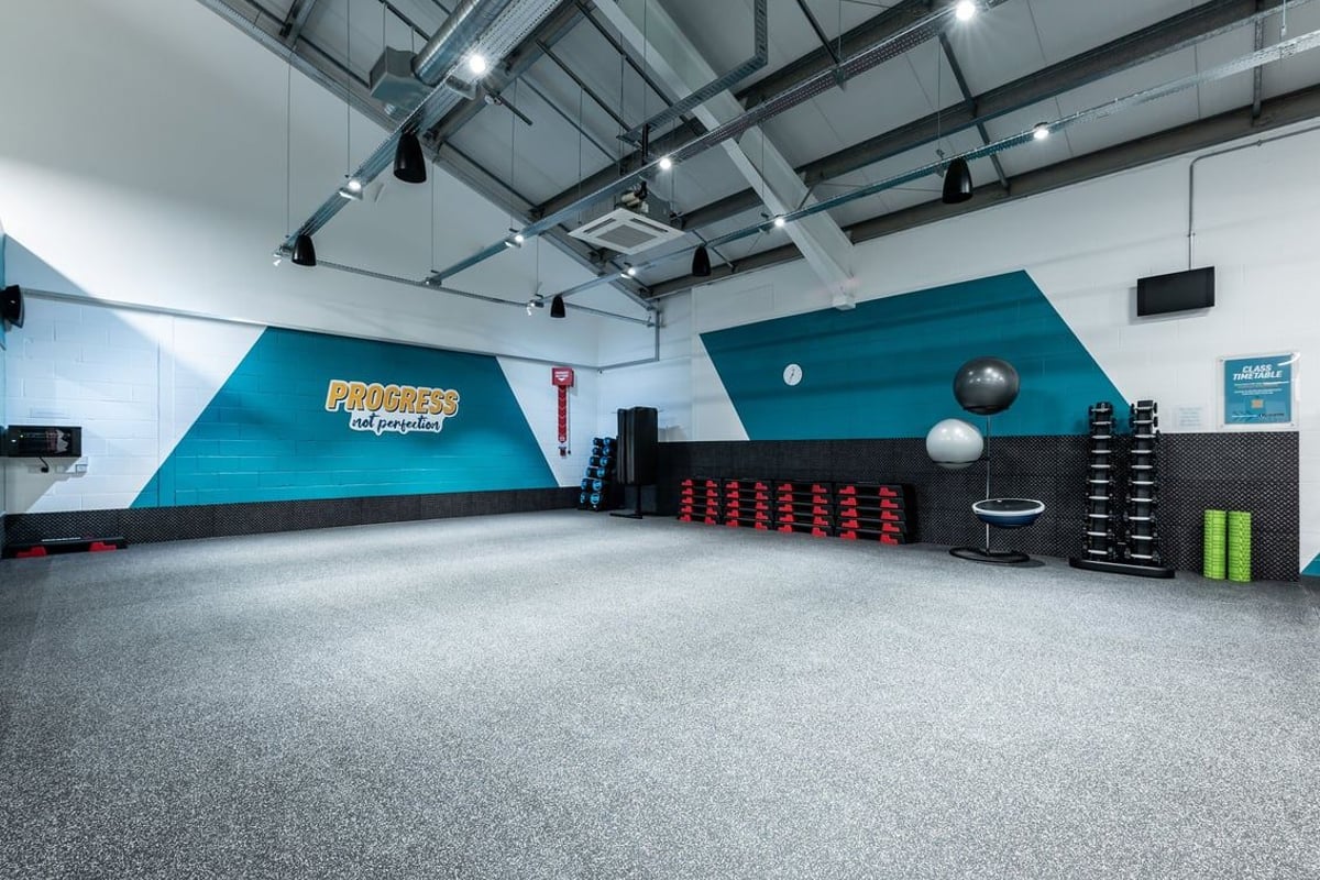 PureGym Uttoxeter: Functional training area with wall padding, medicine balls, plyo boxes, and rubberized flooring.
