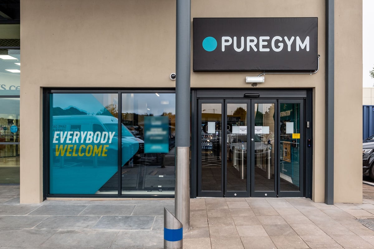 PureGym Dungannon: Front entrance of a Pure Gym fitness center with large window displaying "Everybody Welcome" message.