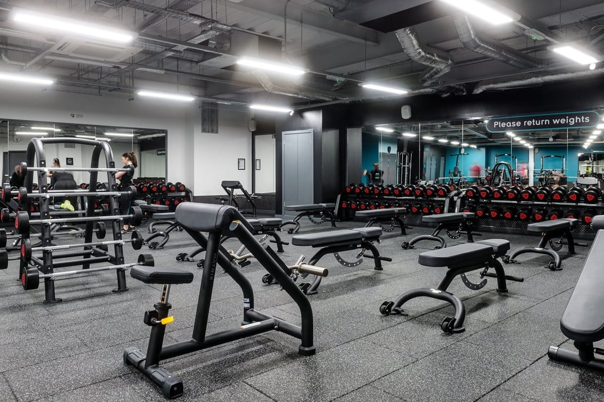 PureGym Glasgow Hope Street: Benches, weight racks, dumbbells, and rubberized flooring in a dimly lit fitness studio space.