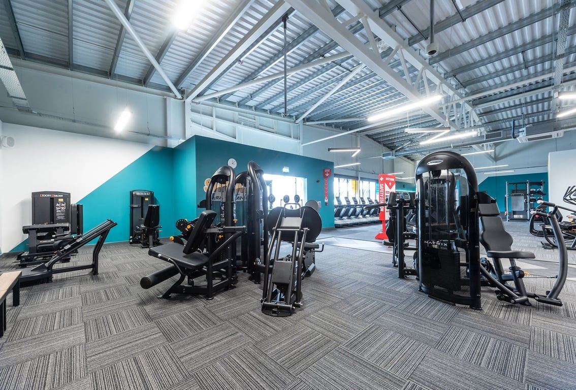 PureGym Barnsley: Resistance machines, weight racks, benches, and patterned rubberized flooring in a brightly lit gym space.