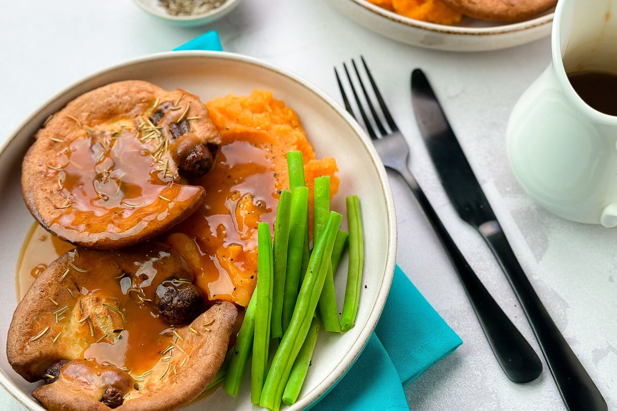 Mini Yorkshire puddings filled with sausages in gravy served with vegetables