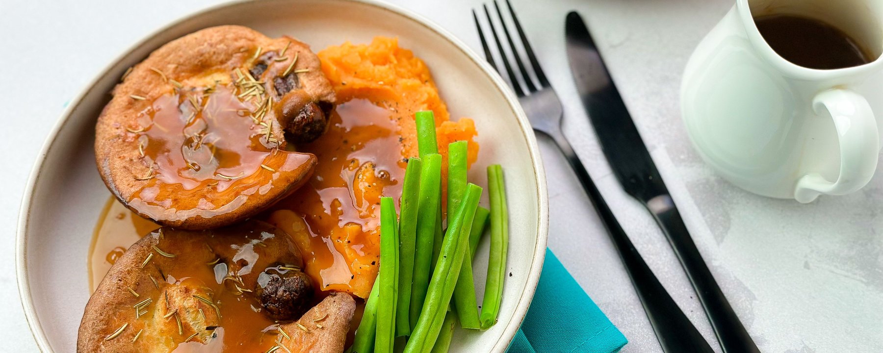 Mini Yorkshire puddings filled with sausages in gravy served with vegetables