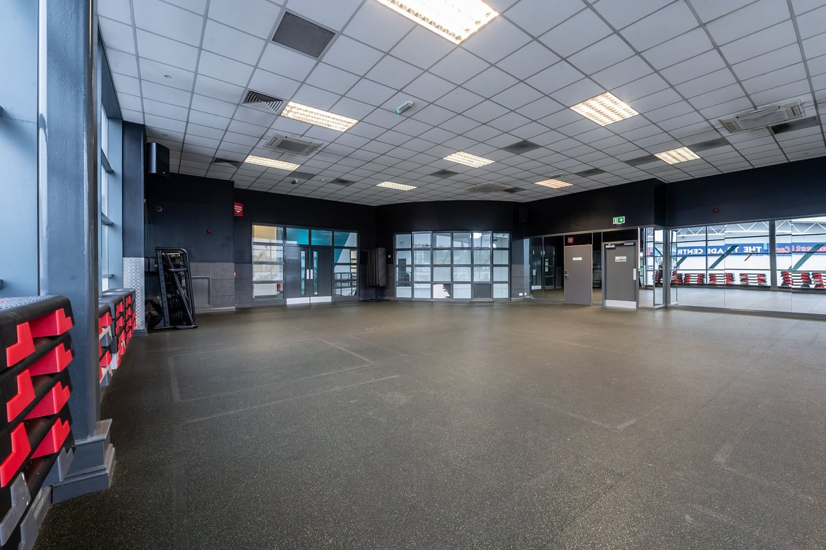 PureGym Rochdale: Large gym studio with stacks of step platforms and rubberised flooring.