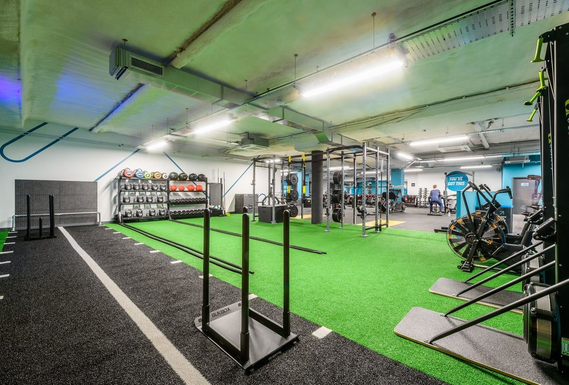 PureGym Hitchin: Functional training area with green turf, weight racks, suspension trainers, and rubberized flooring.