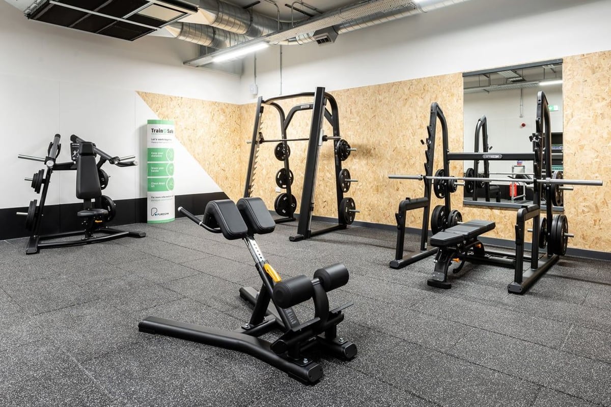 PureGym Witney: Strength machines, squat racks, weight benches, free weights, and rubberized flooring in a gym.