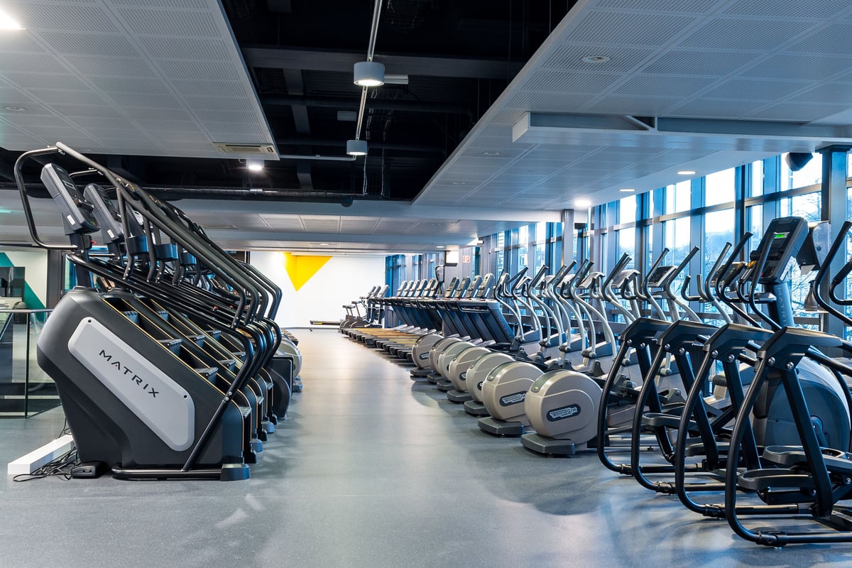 Salle cardio de la gym Lochergut avec steppers et elliptiques face aux fenêtres