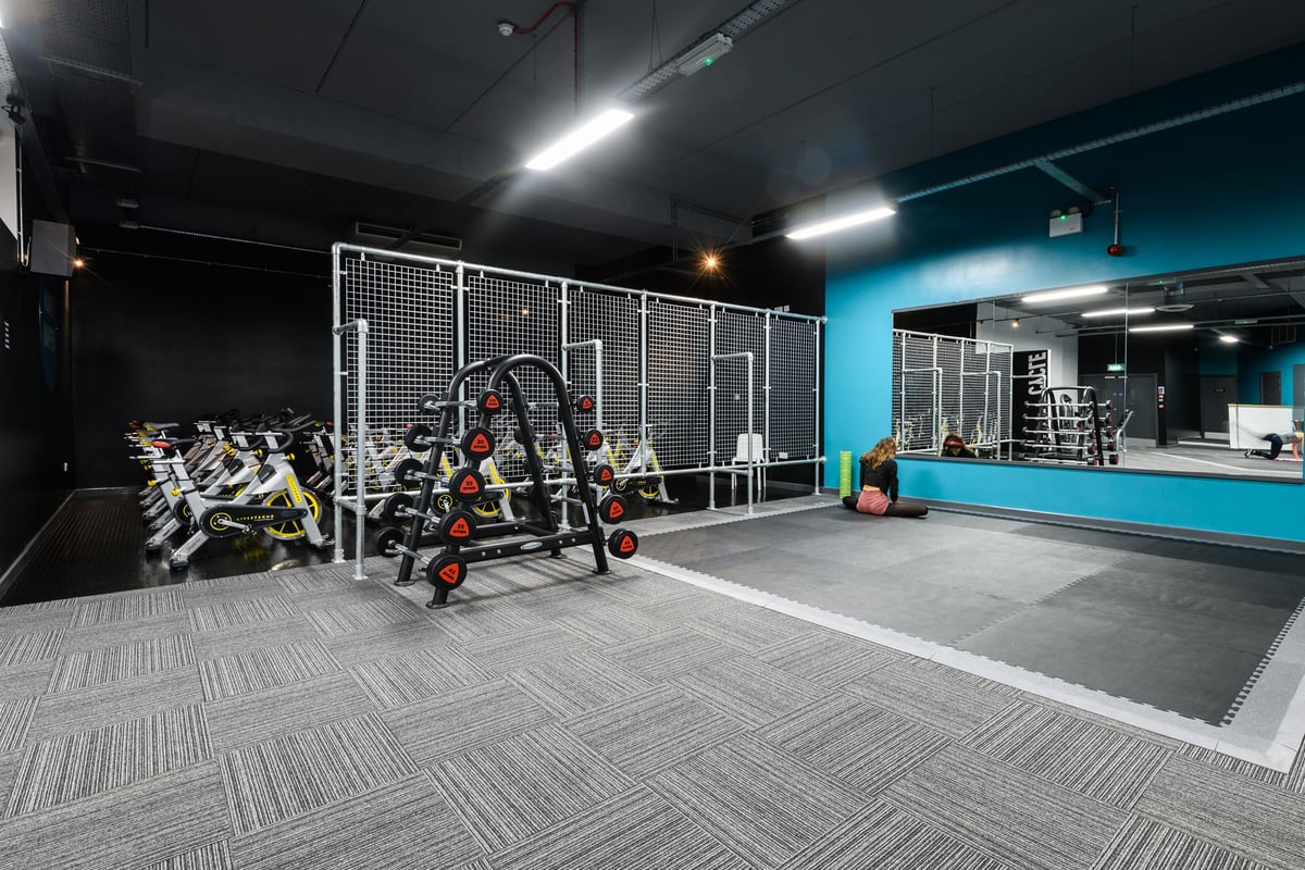 PureGym Bournemouth The Triangle: Caged functional training area, medicine balls, rubberized flooring in dimly lit studio.