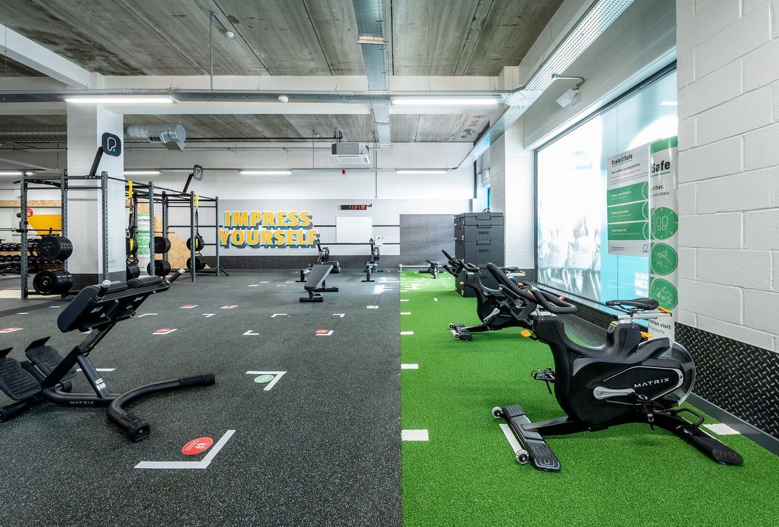 PureGym Chelmsford Meadows: Rowing machines, spin bikes, free weights, rubberized flooring, green turf area.