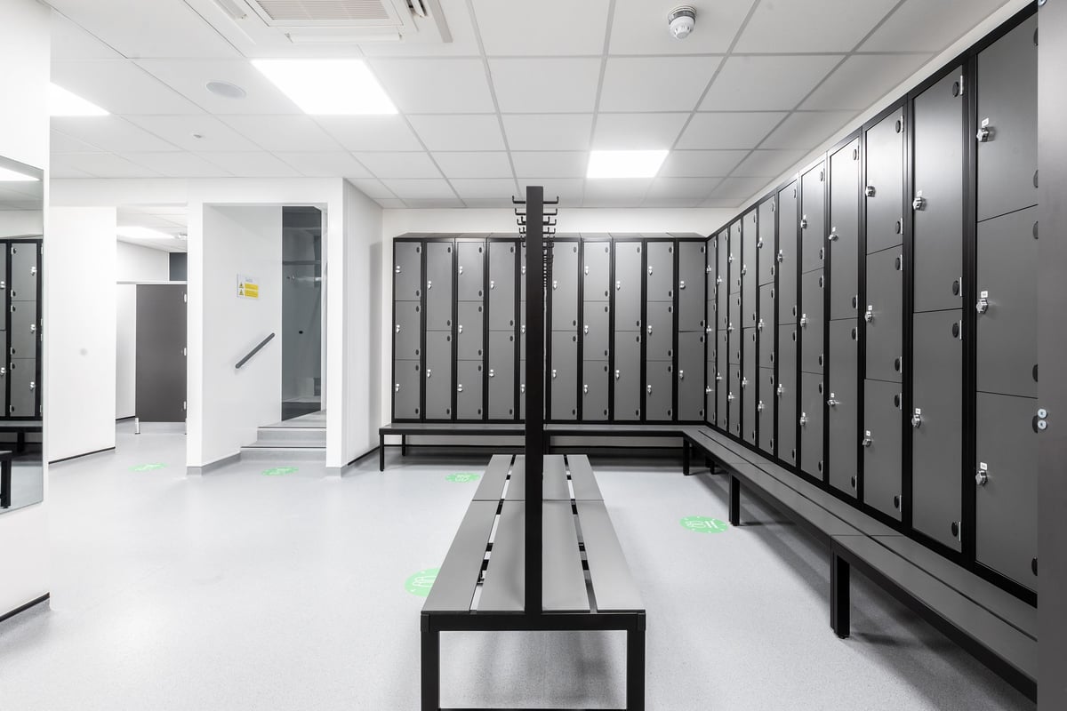 PureGym Swindon Stratton: Rows of lockers, benches in an austere changing room.
