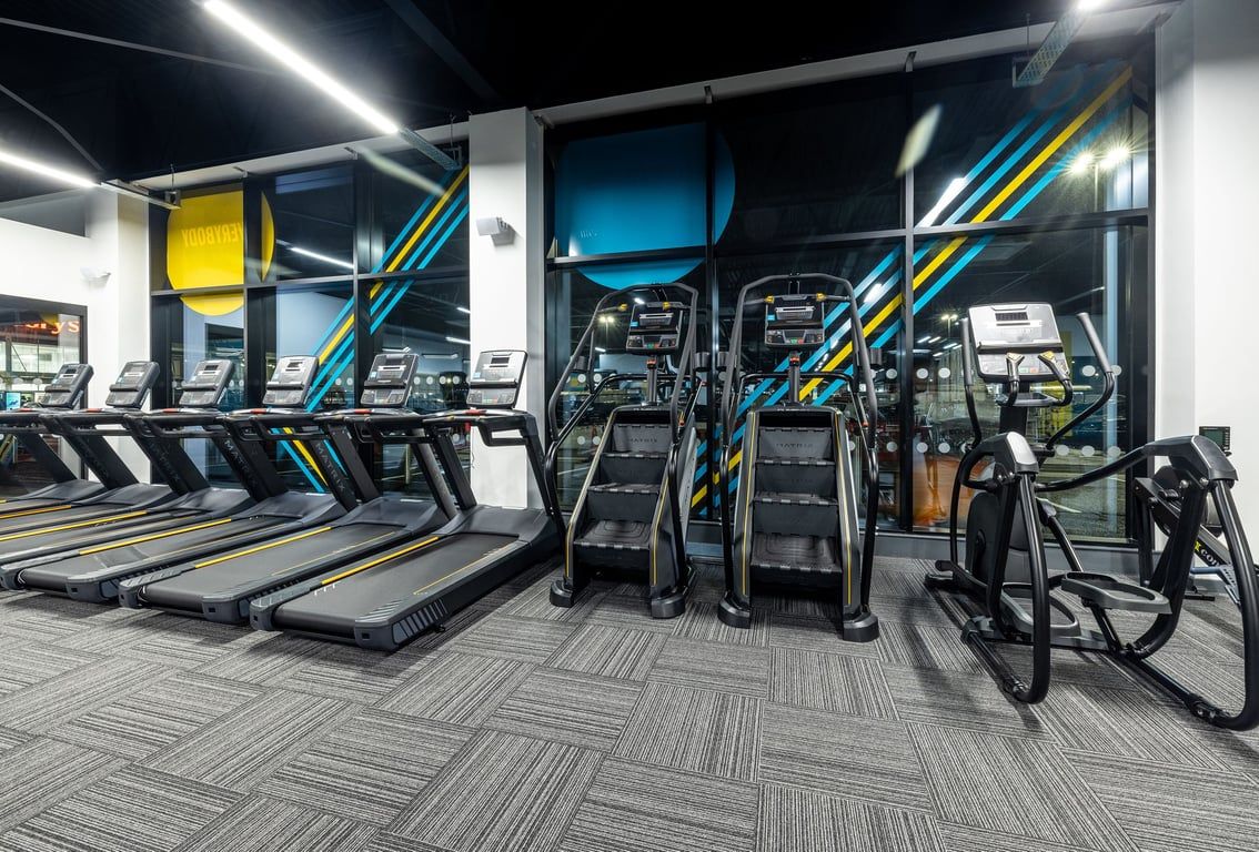 PureGym Washington: Long rows of modern treadmills, bright lighting, and geometric floor pattern in a gym cardio area.