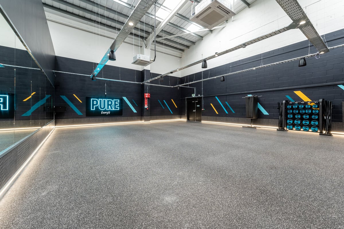 PureGym Chippenham: Indoor fitness park with padded ramps, neon lighting, and workout equipment.