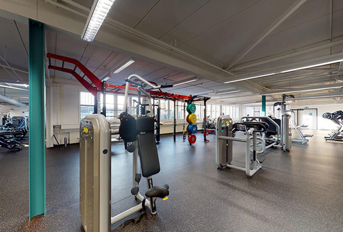 Puregym Baar: Des rangées d'appareils de cardio-training, de bancs de musculation et d'équipements de résistance dans un intérieur de salle de sport spacieux.