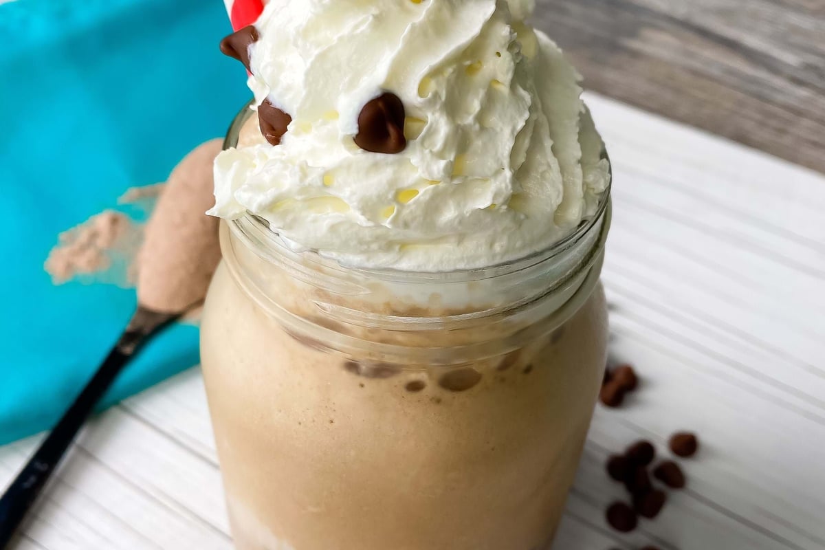 Iced coffee drink topped with whipped cream and chocolate chips in a glass jar