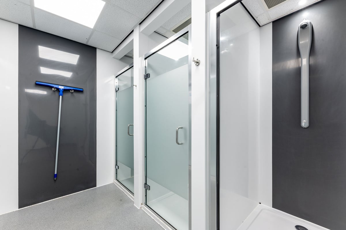PureGym Brierley Hill: Shower area with glass stalls, grey tiles, emergency pull cord.