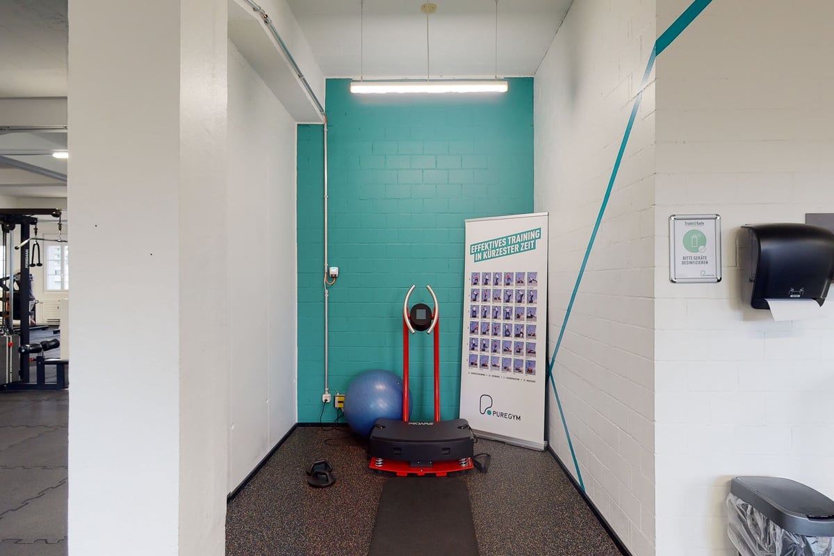 PureGym Olten: Blaublaues Zimmer mit Gymnastikball, Wandkarten und potenzieller Ausrüstung für das Eingangstor.