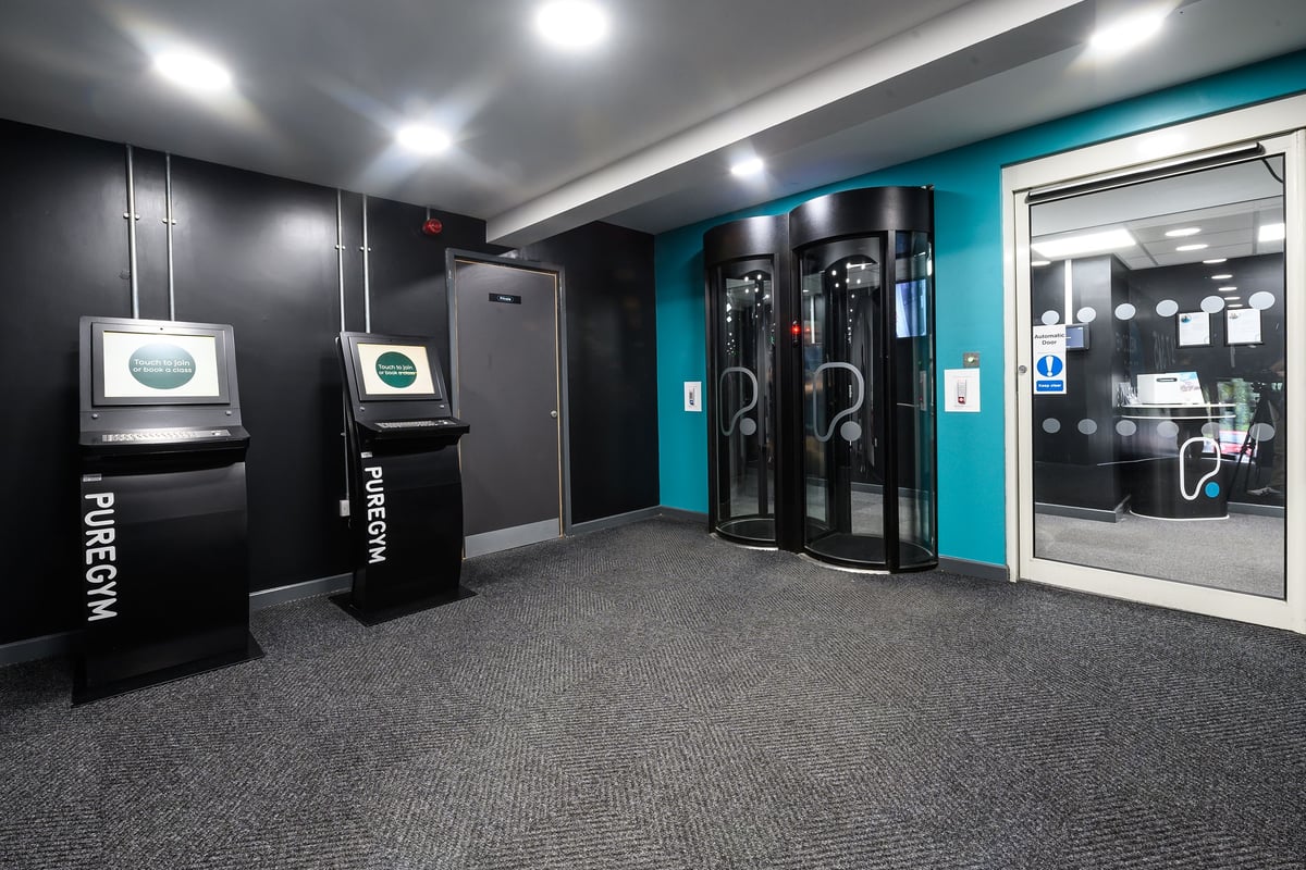 PureGym Burnham: Phytogram machines, lockers, and shower stalls in a dark, modern changing room.