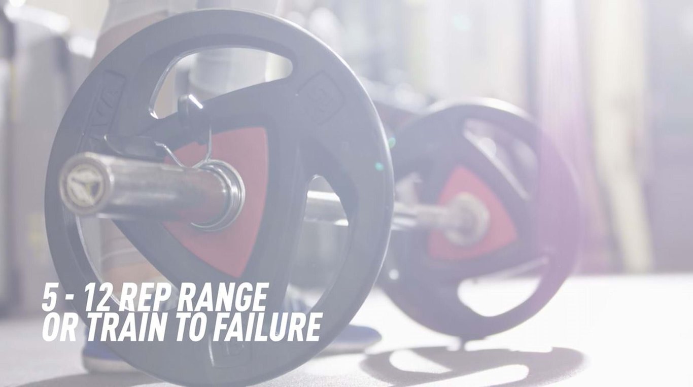 Barbell with weight plates on a gym floor with text about rep range and training to failure