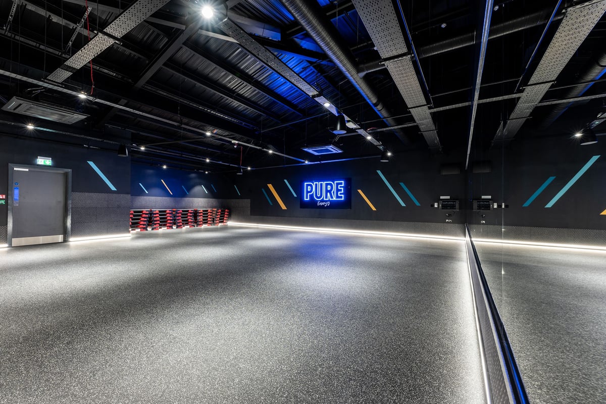 PureGym Doncaster: Venue with neon lighting, rubberized flooring, and red equipment benches.