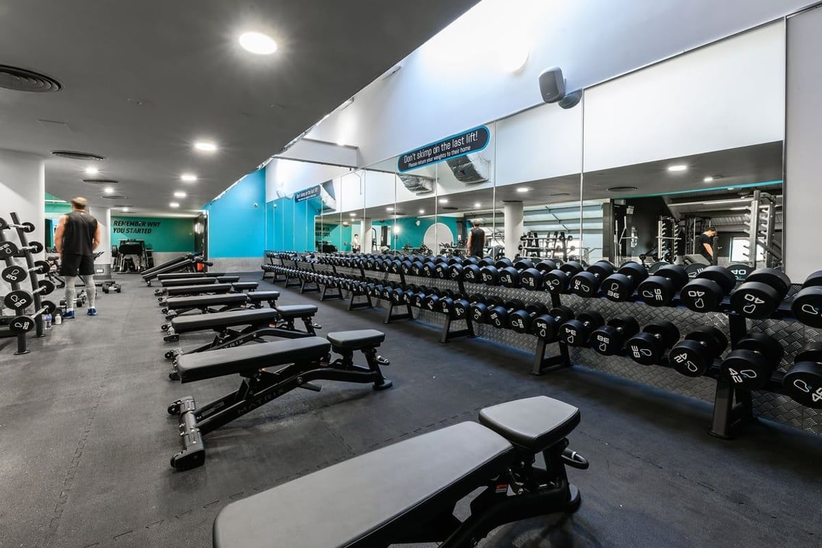 PureGym Norwich Riverside: Rows of dumbbell racks, weight benches, rubberized flooring in a bright gym interior.