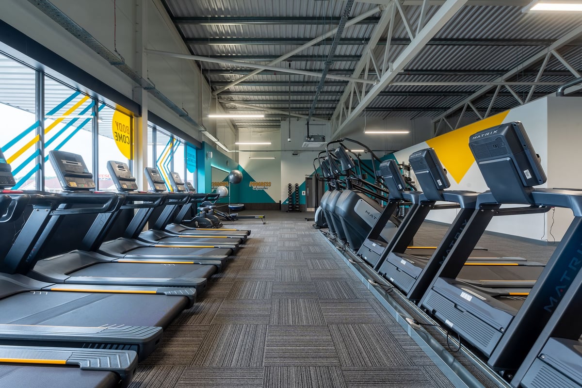 PureGym Barnsley: Rows of treadmills, stationary bikes and elliptical machines in a bright gym studio.