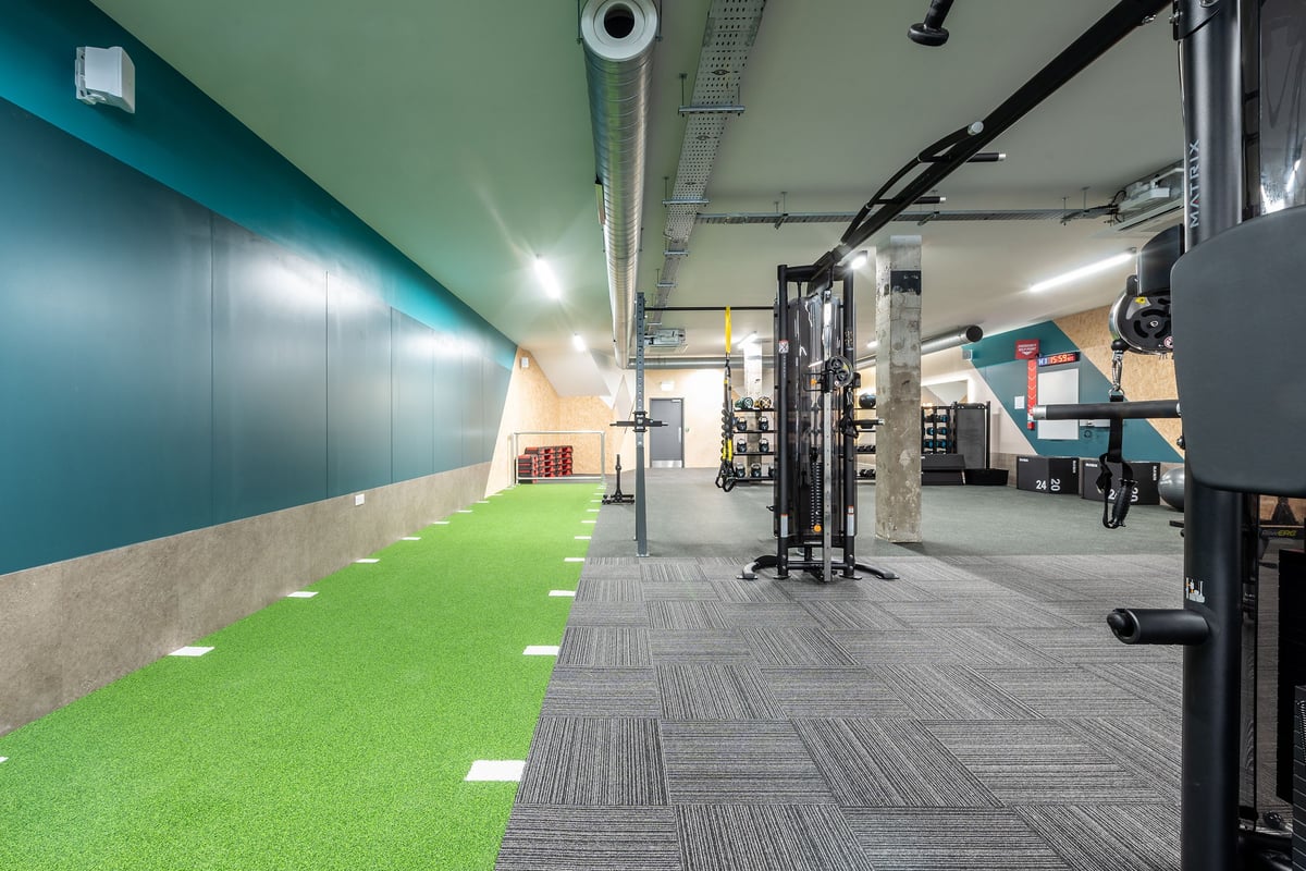 PureGym London Welling: Turf area, weight racks, benches, and mirrored walls in a modern gym studio.