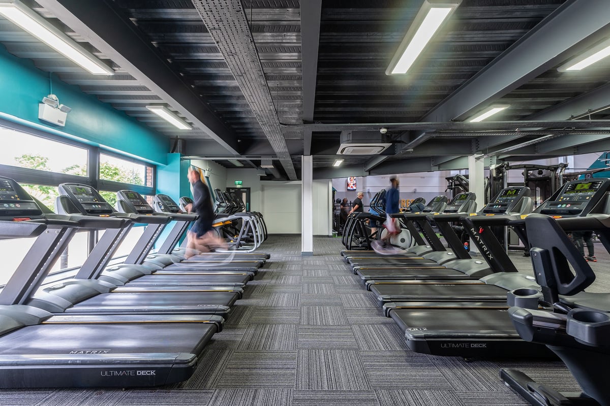PureGym Aintree: Rows of treadmills, ellipticals, and other cardio machines in a gym setting with teal accents.