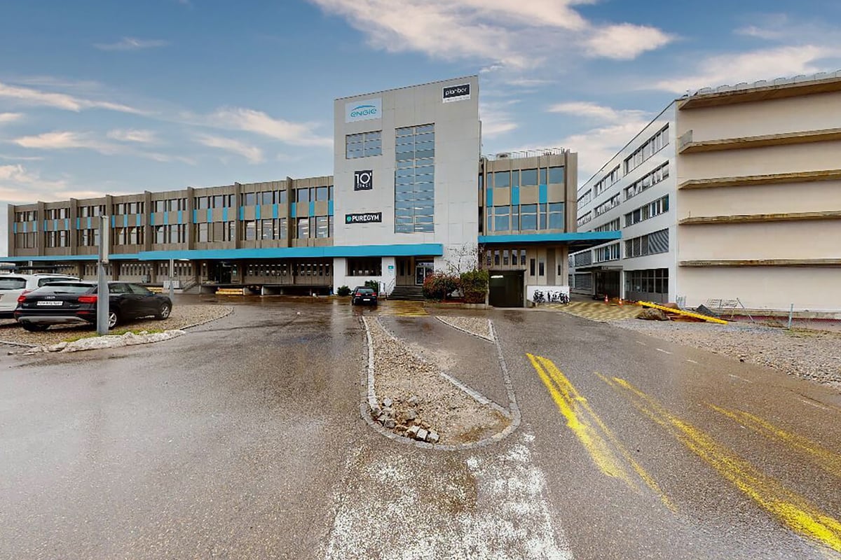PureGym Jona: Aussenansicht eines mehrstöckigen Geschäftshauses mit Parkplatz und Fahrzeugen.