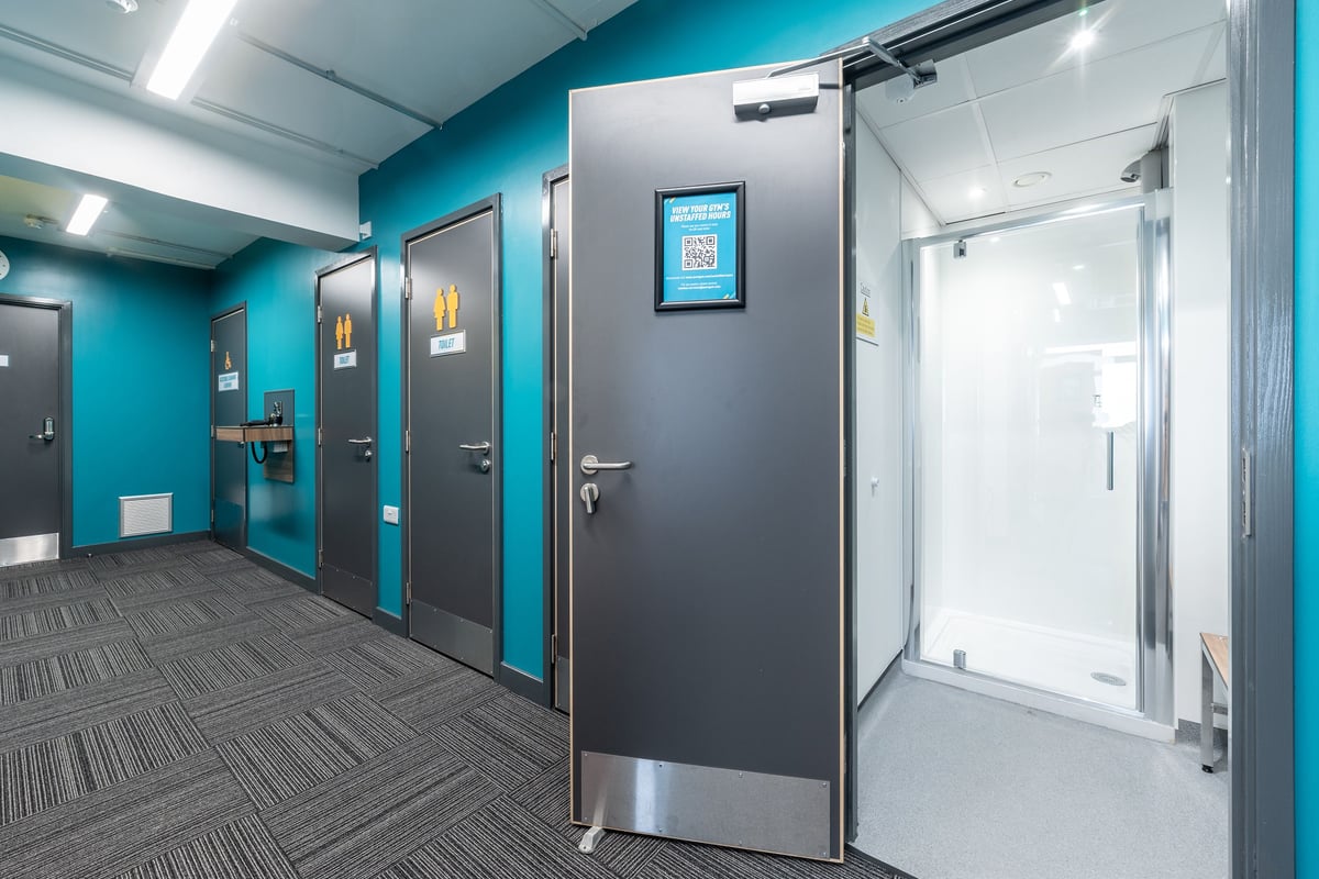 PureGym London Hornchurch: Rows of private changing cubicles with doors in turquoise and grey tones.