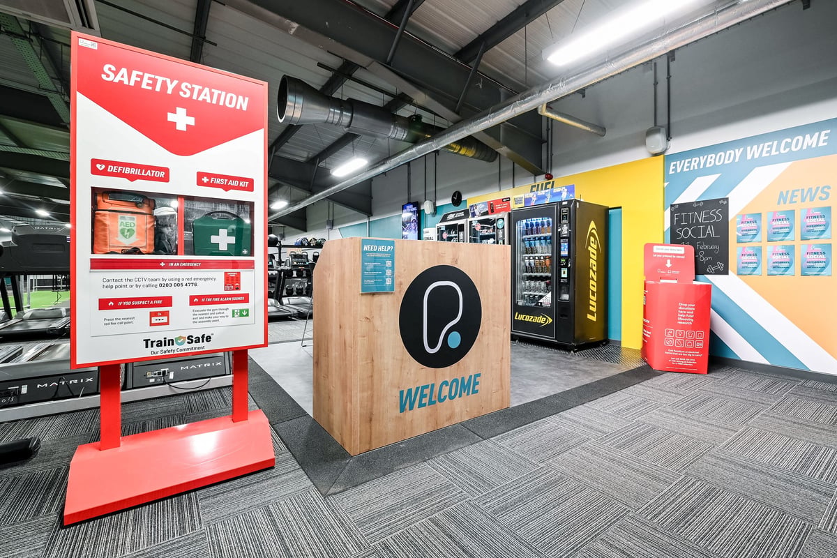 PureGym Canterbury Sturry Road: Safety station, vending machines, welcome desk, and branding in the lobby.