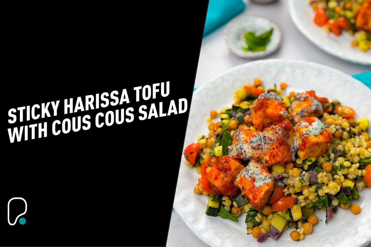 Sticky harissa tofu cubes on couscous salad with chickpeas and vegetables on white plates