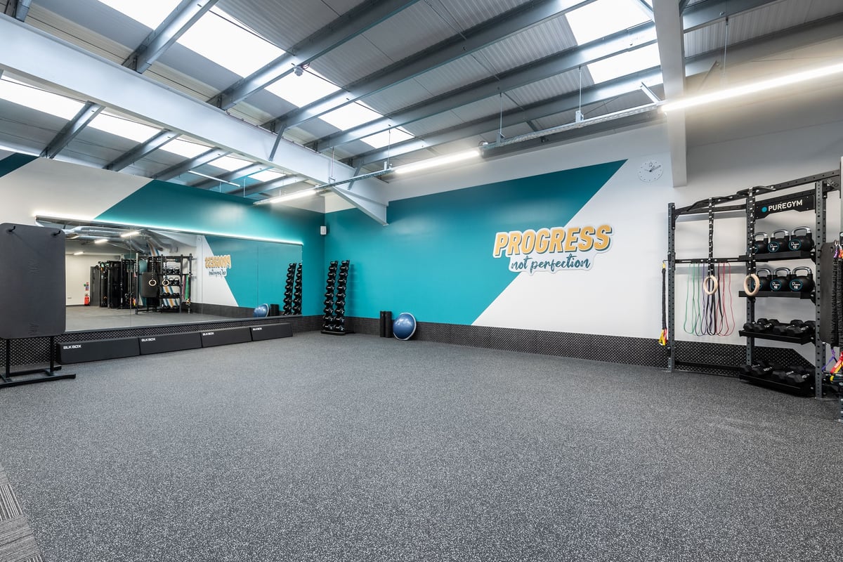 PureGym Derby Kingsway Retail Park: Kettlebells, free weights, and straps with a mirrored wall in the gym studio.