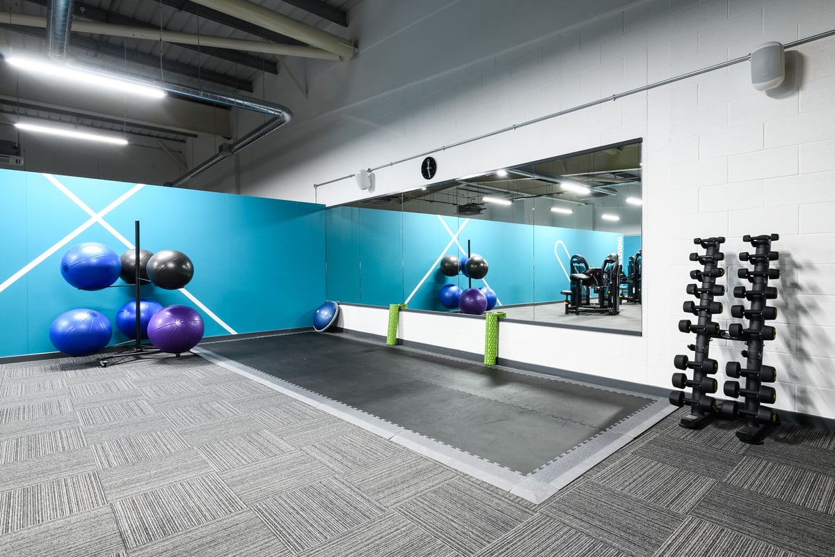 PureGym Cardiff Bay: Exercise studio with stability balls, dumbbell racks, resistance bands, and mirrored walls.