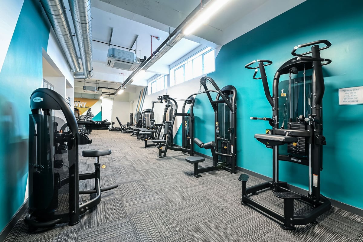 PureGym London Bethnal Green: Rows of exercise machines, free weights, and benches in a room with teal walls.