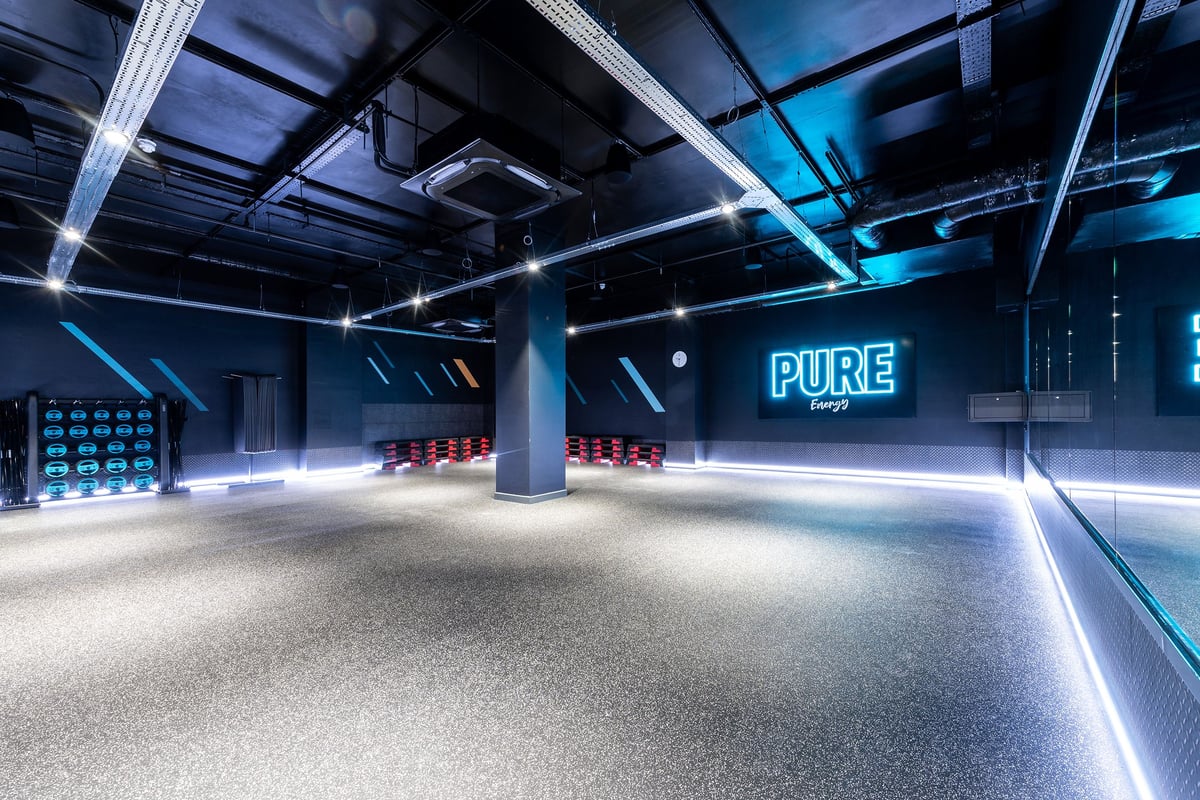 PureGym London Crouch End: Large gymnasium interior with red bench seating and neon "PURE" signage.