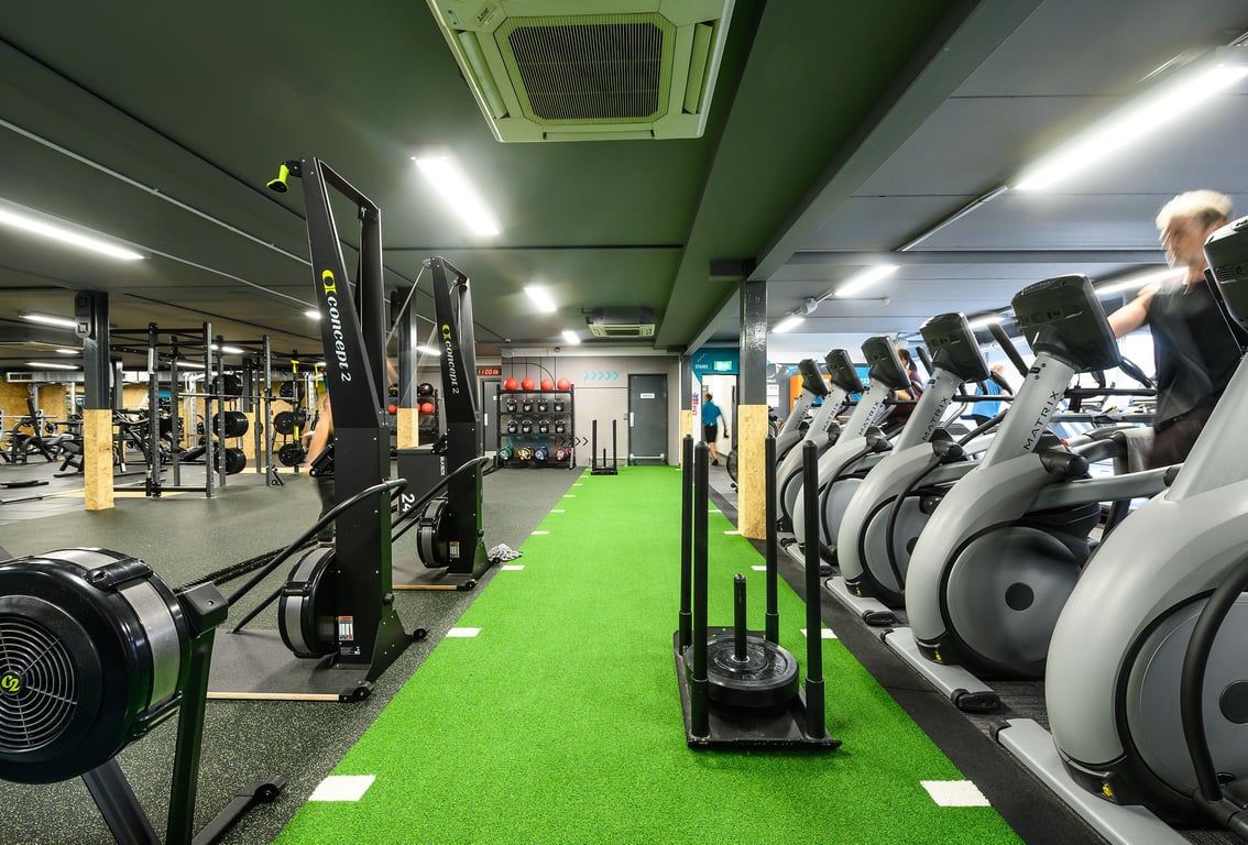 PureGym Reading Caversham Road: Rows of cardio machines, weight racks, benches, mirrors in a green and grey fitness studio.
