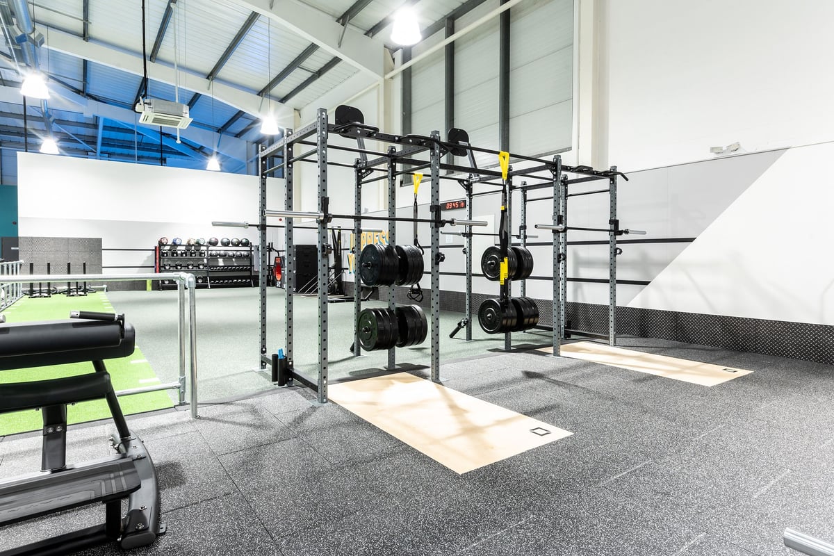 PureGym Torquay Bridge Retail Park: Rig with weight plates, suspension trainers, benches, rubberised floor in gym space.