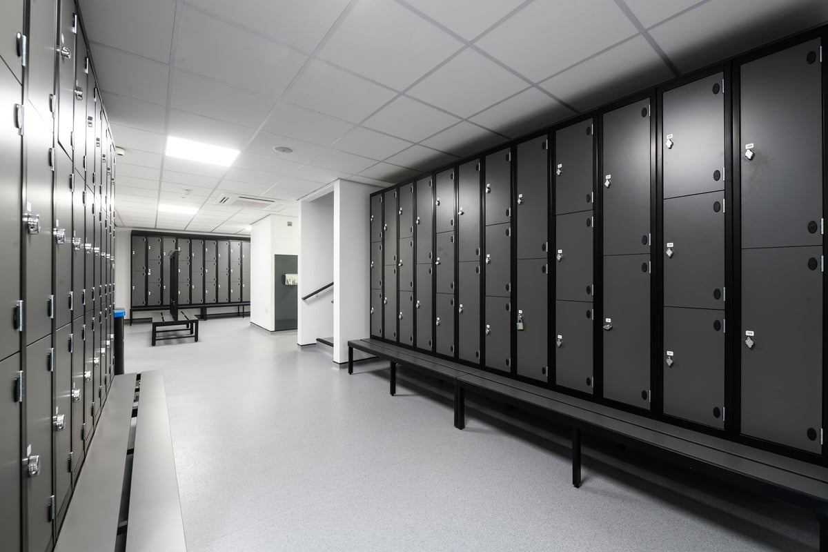 PureGym Birmingham Arcadian Centre: Rows of lockers, benches in a utilitarian changing room interior.