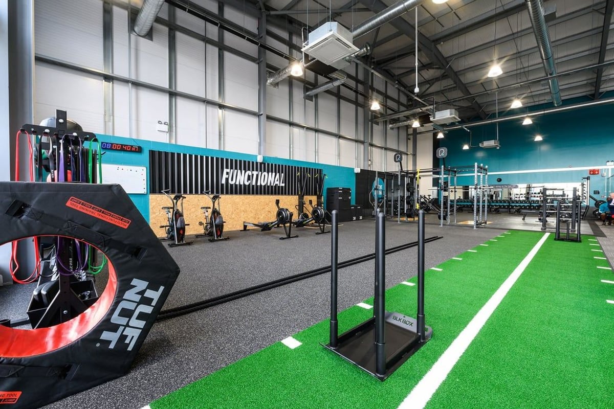 PureGym Maldon Blackwater Retail Park: Functional training area with turf, squat racks, weight plates, rubberized flooring.