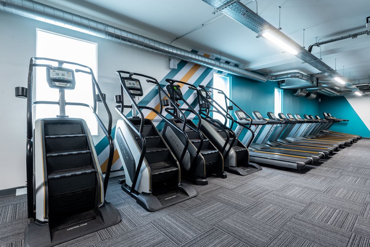 PureGym London Holloway Road: Rows of stair climbers, treadmills, cardio machines in a dimly lit gym interior.